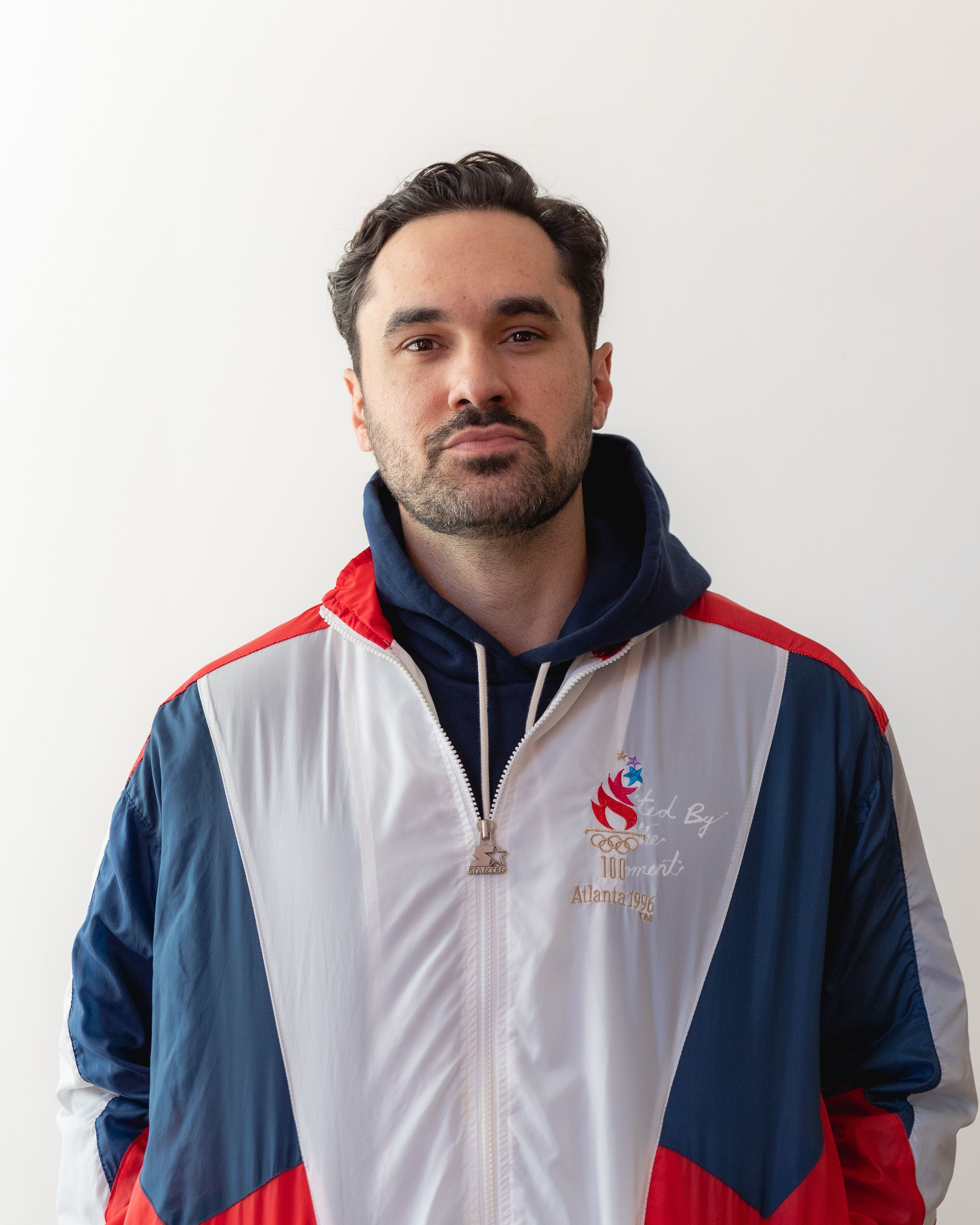 Rob Howe in a red, white and blue windbreaker against a white wall